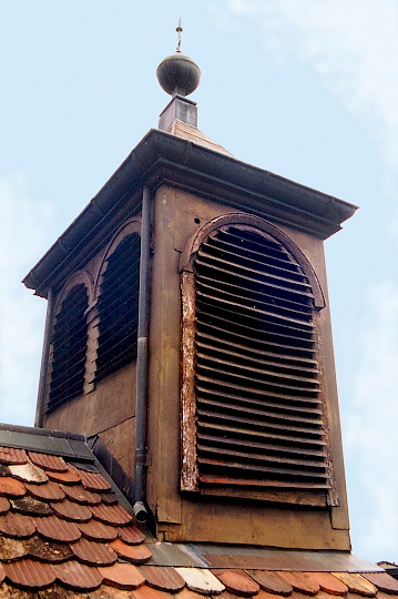 Un grattage superficiel révèle l'application d'une peinture couleur cuivre brun foncé avec une nuance de vert olive sur l'ensemble des surfaces, à l'exception du chéneau, des descentes d'eau pluviale et du poinçon qui ont été laissés en cuivre naturel.