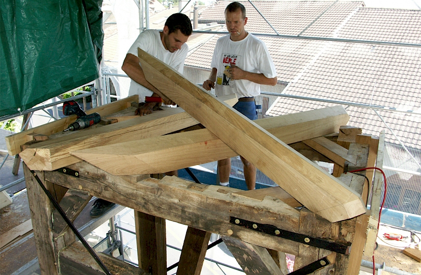 L’ancienne structure tubulaire du toit est remplacée par des arêtiers en chêne. Les câbles qui contreventaient le clocher étaient trop rouillés pour être reposés et le principe était aussi trop élastique. Ils sont remplacés par des méplats de 30x5mm. Les anciennes ferrures sont également traitées. Les poutres sont entaillées pour que la menuiserie plaque parfaitement avec la charpente.