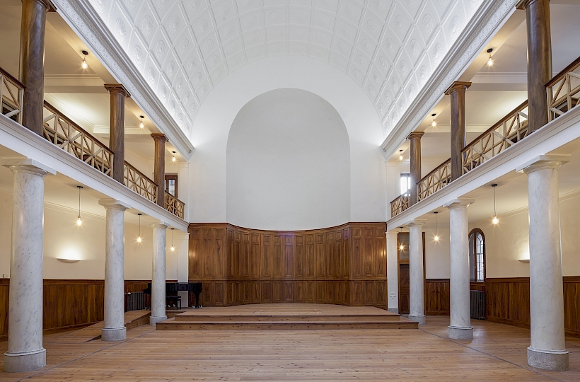 Vue vers le chœur et l’abside hémicyclique en cul de lampe, autrefois équipée de deux baies situées à peu près à l’altitude de la galerie, au- dessus du soubassement en panneau de bois. Photo après travaux.