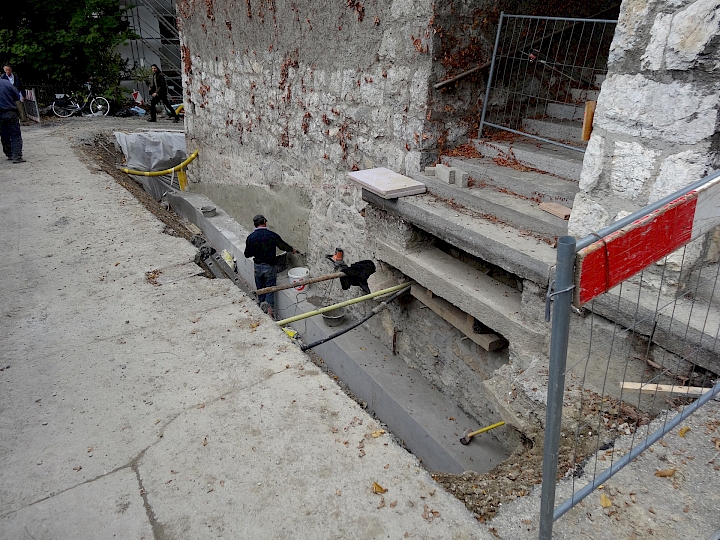 Façade sud, côté route. Application d'un enduit bouche pores sur la face contre terre.