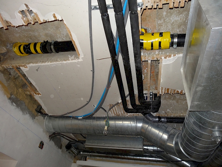 Installation d'un écoulement et de conduites d'alimentations en eau dans le local cuisine en vue des aménagements prévus dans la nef. Les gaines de ventilations visibles au plafond sont en place depuis les années 80.