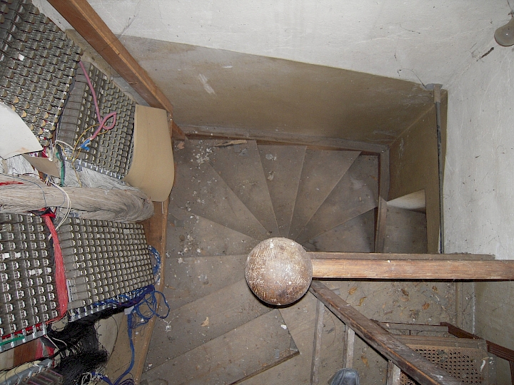 Vue plongeante sur l'escalier du beffroi au niveau de la galerie. A gauche, partie du mécanisme de l'orgue.
