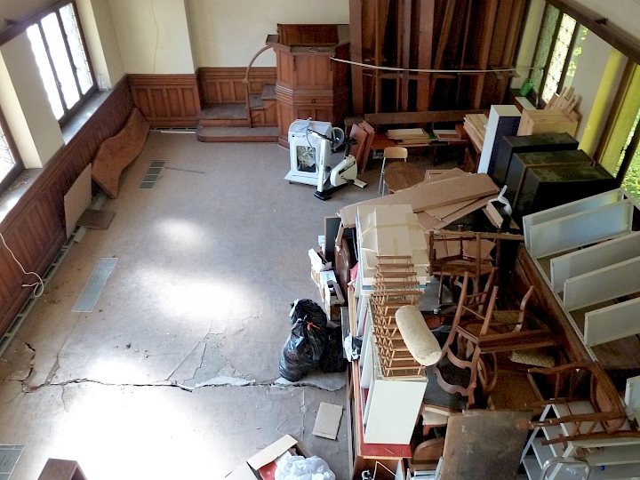 Vue d'ensemble de la nef en direction de la chaire. La dalle sur rez-inférieur est fendue sur toute la largeur au droit du mur de refend. Les boiseries, portes et fenêtres sont relativement bien conservés, à l'exception d'une partie des vitraux de la façade nord. Ces derniers n'ont pas résisté aux mouvements de la Chapelle.